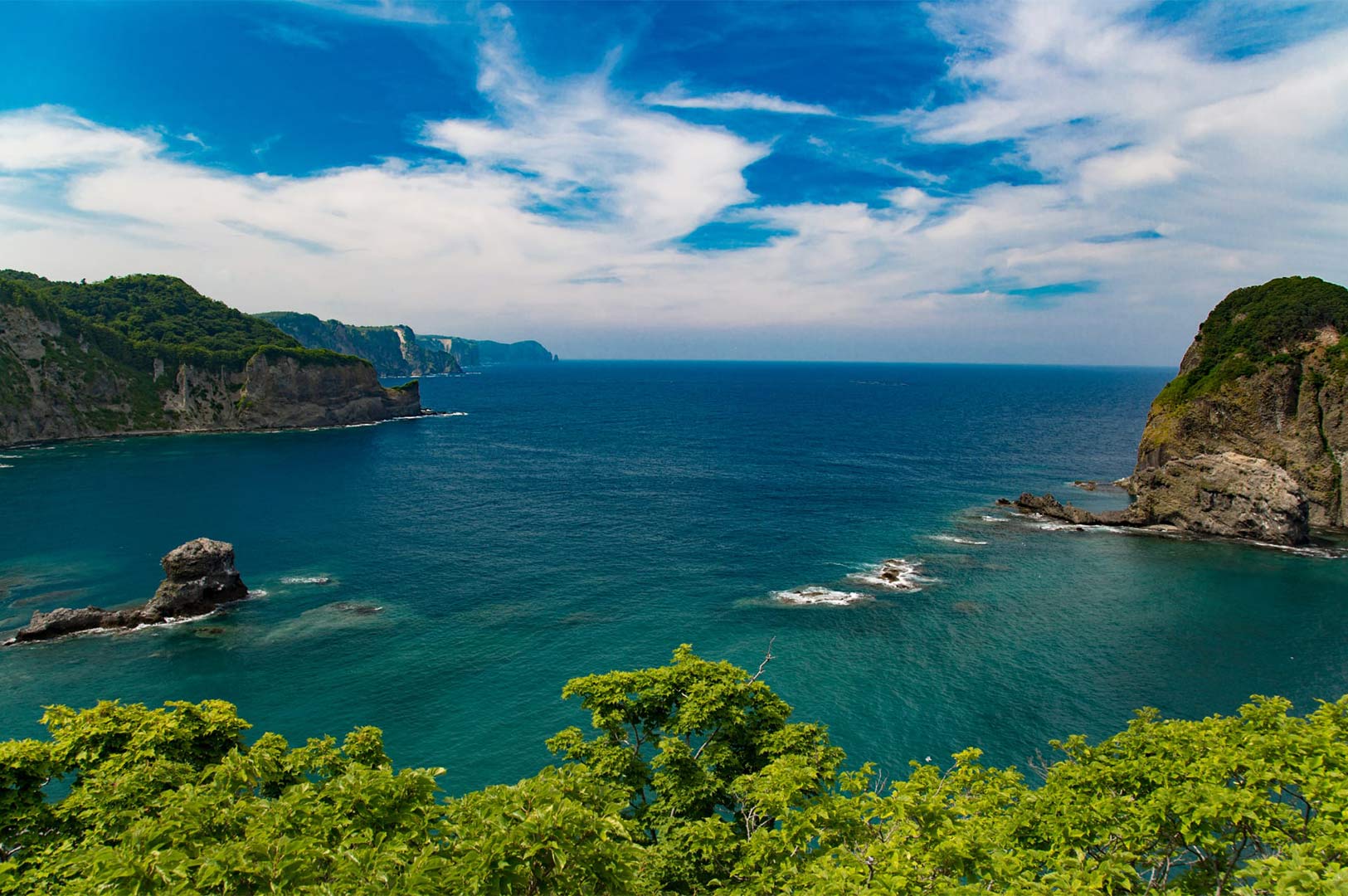 Panoramic view of the crystal blue "Shakotan Blue" ocean and rugged rocky cliffs at Cape Kamui on the Shakotan Peninsula, Hokkaido.