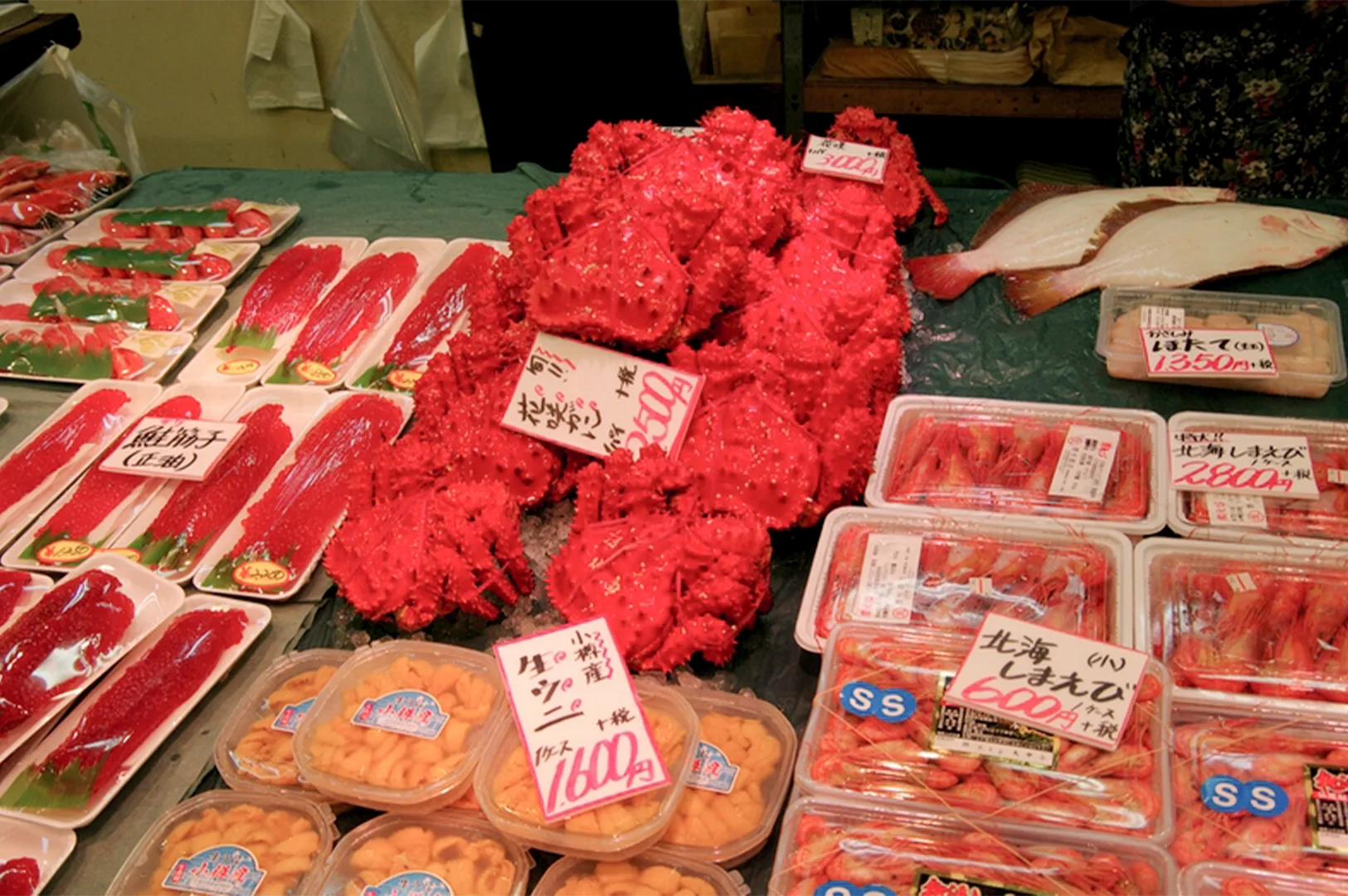 Fresh Japanese seafood display at Otaru Sankaku Market featuring bright red King Crabs, sea urchin (uni), and sashimi.