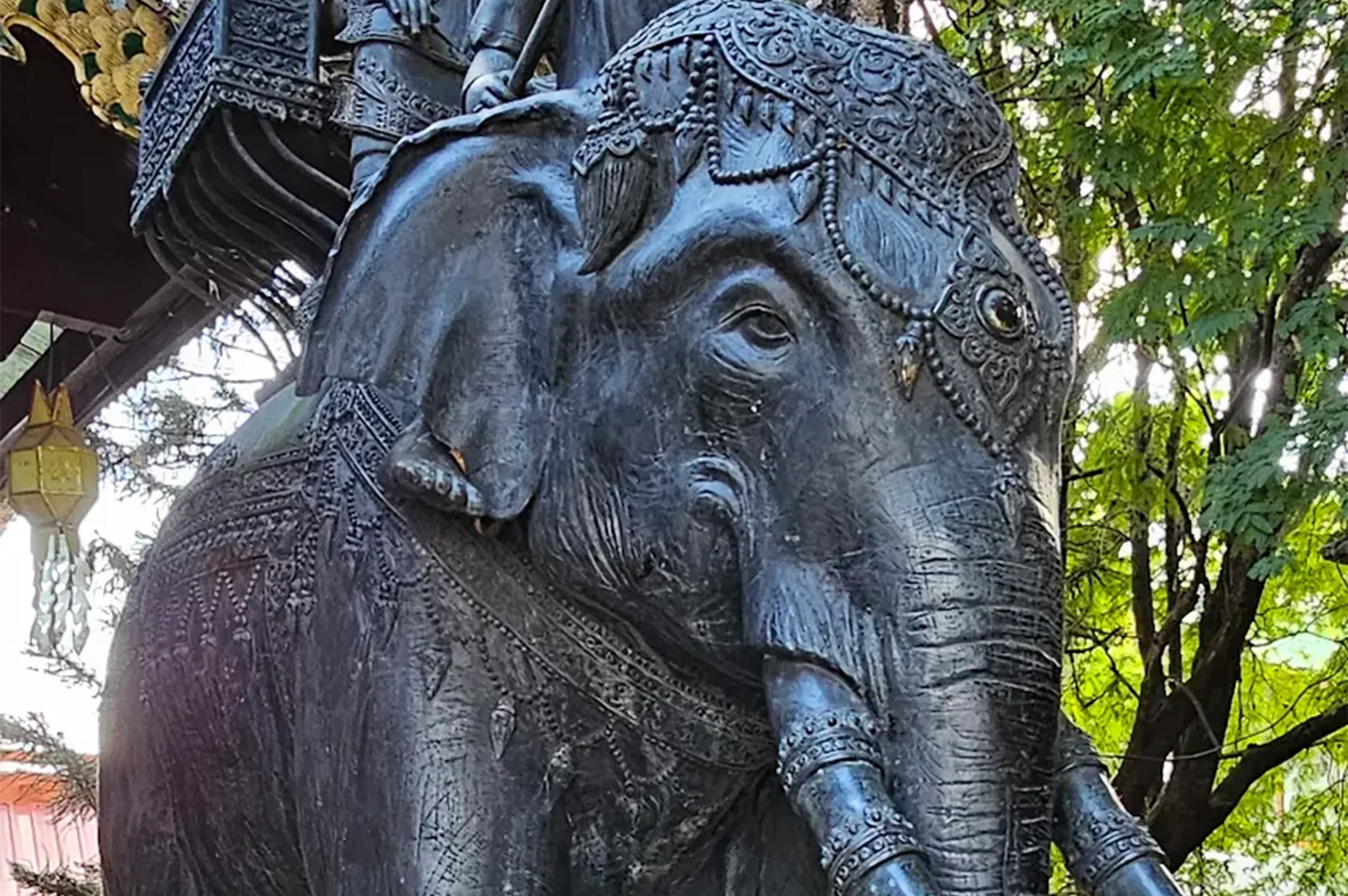 Close-up detail of a majestic black elephant statue decorated with intricate traditional Thai jewelry and headwear.