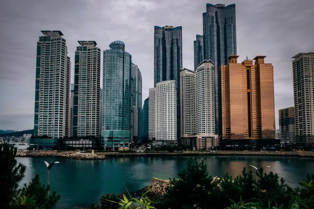 Busan skyline featuring modern waterfront skyscrapers, luxury high-rise buildings, and coastal views under an overcast sky in South Korea.