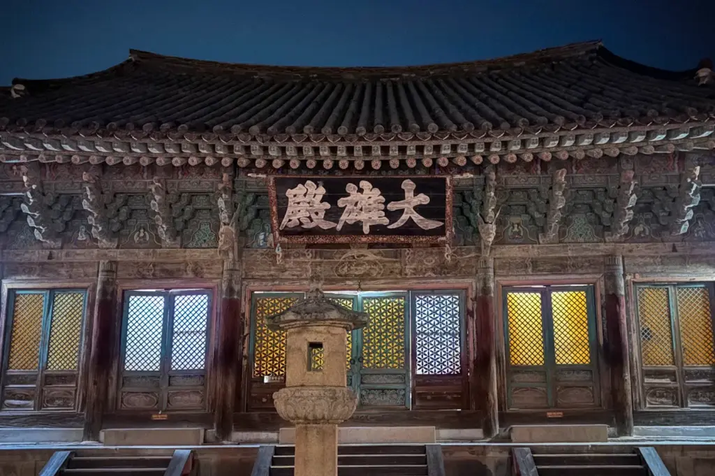 Bulguksa Temple in Gyeongju, South Korea illuminated at night, featuring ornate traditional Korean architecture, historic stone lantern, and intricate wooden details.