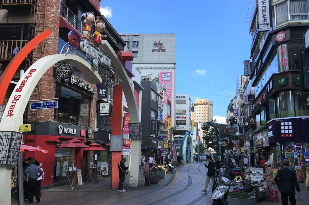 Nampo-dong shopping street in Busan, South Korea, featuring the iconic entrance arch, colorful storefronts, restaurants, cafes, and bustling pedestrian walkways.