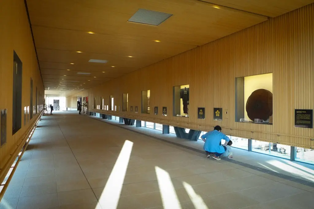 Modern Takayama Station interior in Japan featuring a spacious wooden corridor with cultural exhibits, natural light, and travelers exploring the station's contemporary architecture.
