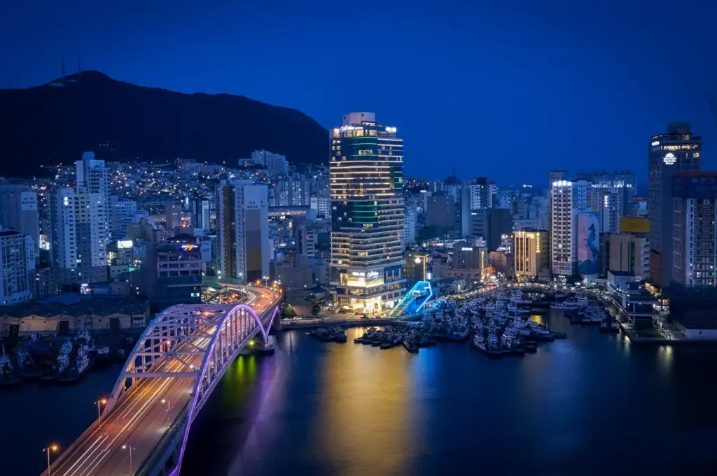 Busan night skyline featuring Yeongdo Bridge, illuminated waterfront buildings, city lights, and a scenic harbor view in South Korea.