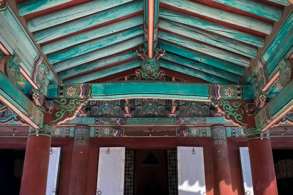 Front entrance of Gyeonggijeon Shrine featuring colorful dancheong-painted wooden beams, traditional Korean architecture, red columns, and an open historic hall in Jeonju.