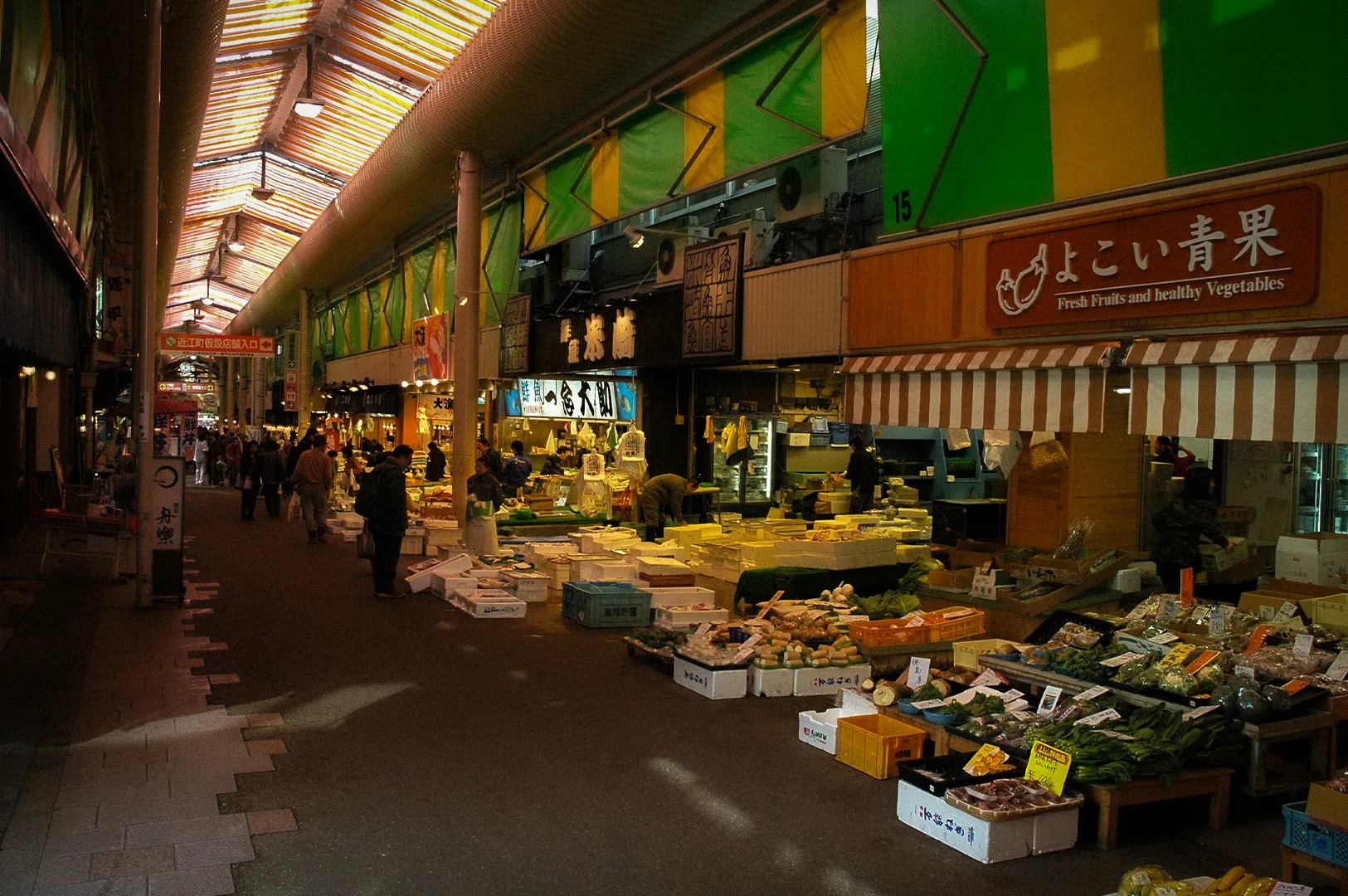Omicho Market in Kanazawa, Japan, featuring fresh seafood, vegetables, and local produce stalls inside a bustling traditional covered marketplace.