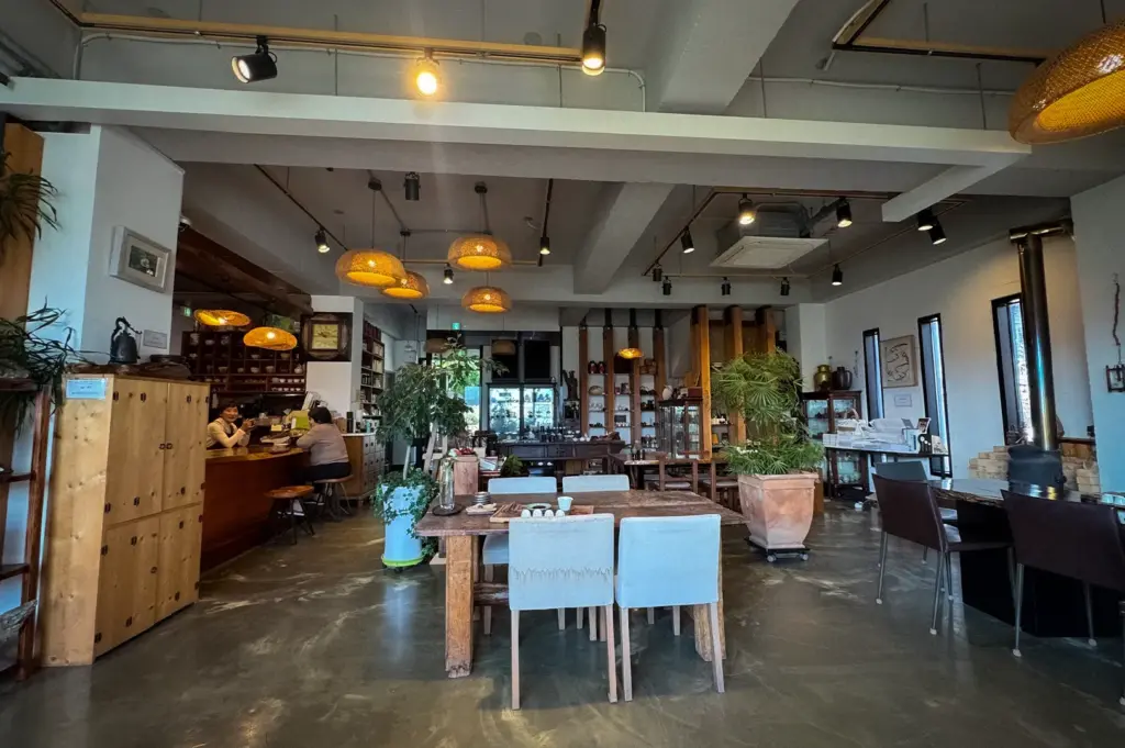 Traditional teahouse interior in Gyeongju, South Korea featuring wooden furniture, warm pendant lighting, indoor plants, and a cozy café atmosphere.