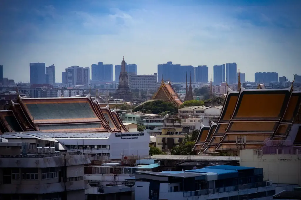 Bangkok skyline featuring traditional Thai temple rooftops and historic architecture with modern high-rise buildings in the background.