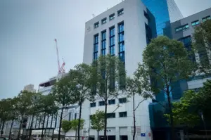 Immigration & Checkpoints Authority (ICA) building in Singapore viewed from the street with modern architecture, roadside trees, and a clear daytime sky.