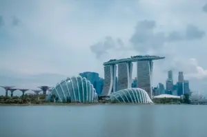 Panoramic view of Marina Bay Sands, Gardens by the Bay, and the Singapore skyline across Marina Bay under a cloudy sky.
