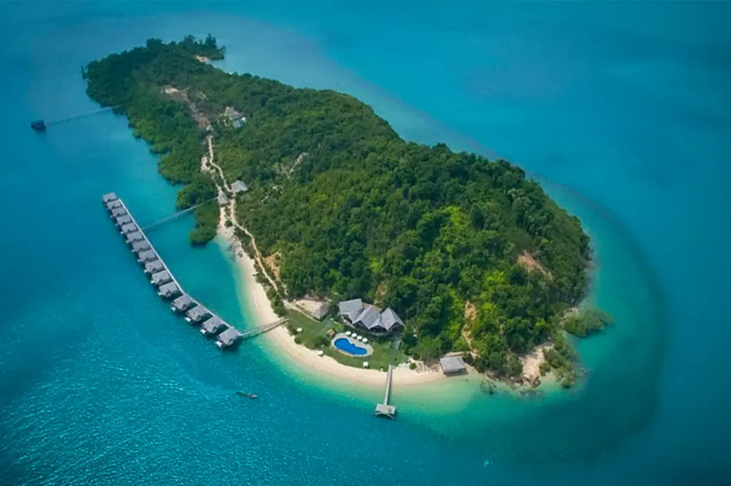 Aerial view of Telunas Private Island in Indonesia featuring overwater villas, white sandy beaches, lush tropical forest, and clear turquoise sea.