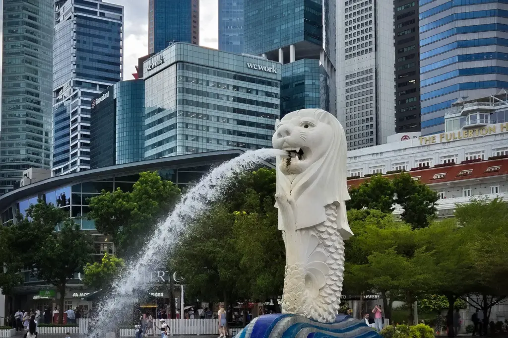 The Merlion statue at Merlion Park in Singapore with Marina Bay's modern skyscrapers and the Fullerton Hotel in the background.