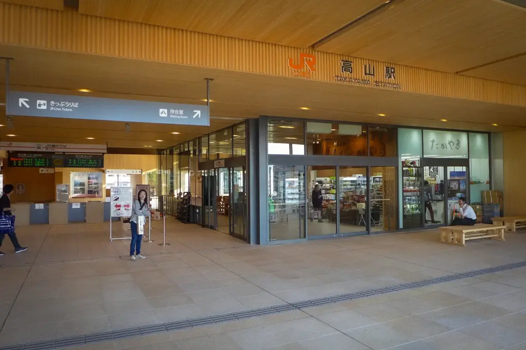 Main entrance of Takayama Station in Gifu, Japan, featuring JR ticket counters, waiting area, souvenir shop, and modern wooden architecture welcoming travelers to the historic city.