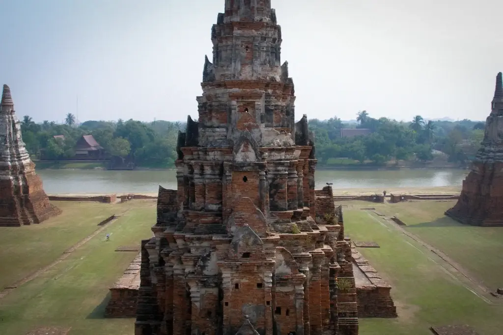 Ancient prang tower at Wat Chaiwatthanaram in Ayutthaya Historical Park, Thailand, overlooking the river with restored temple ruins and historic archaeological grounds.