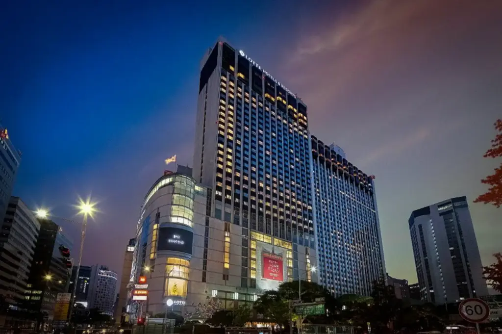 Lotte Hotel Seoul exterior at dusk featuring a modern luxury high-rise in downtown Seoul with illuminated architecture and surrounding city streets.