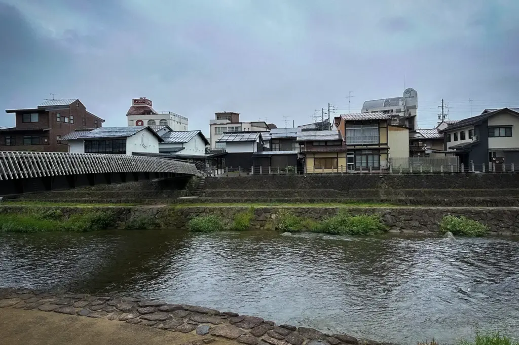 Scenic view of the Miyagawa Morning Market area in Takayama, Japan, featuring the Miyagawa River, traditional riverside buildings, and the iconic market district in the historic city center.