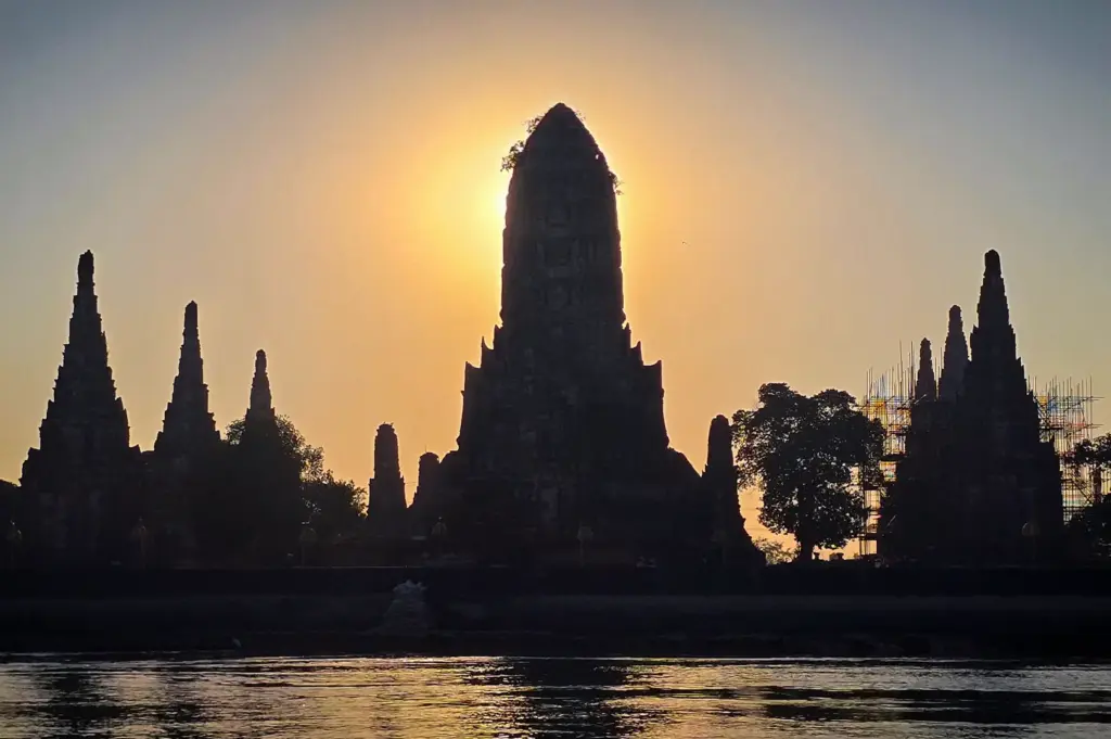 Sunset silhouette of Wat Chaiwatthanaram, an iconic ancient temple in Ayutthaya Historical Park, Thailand, reflected along the Chao Phraya River.