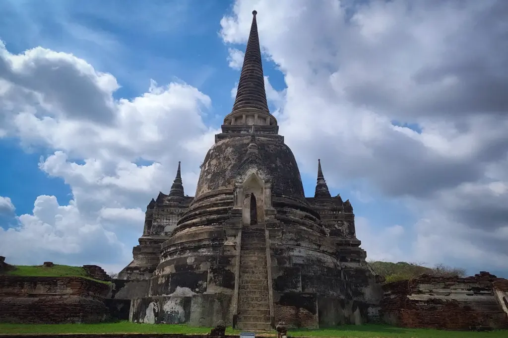Historic stupa at Wat Phra Si Sanphet in Ayutthaya Historical Park, Thailand, showcasing ancient temple architecture beneath a dramatic cloudy sky.