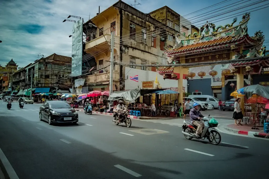 Busy street in Bangkok Chinatown, Thailand featuring traditional Chinese architecture, local shops, market stalls, and everyday city traffic.