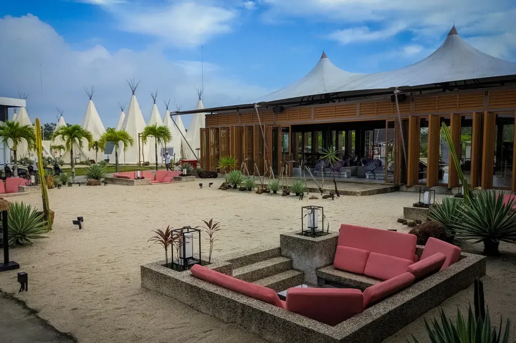 Outdoor courtyard at ANMON Bintan Glamping Resort in Bintan, Indonesia, featuring luxury safari tents, modern lounge seating, desert-inspired landscaping, and tropical surroundings.