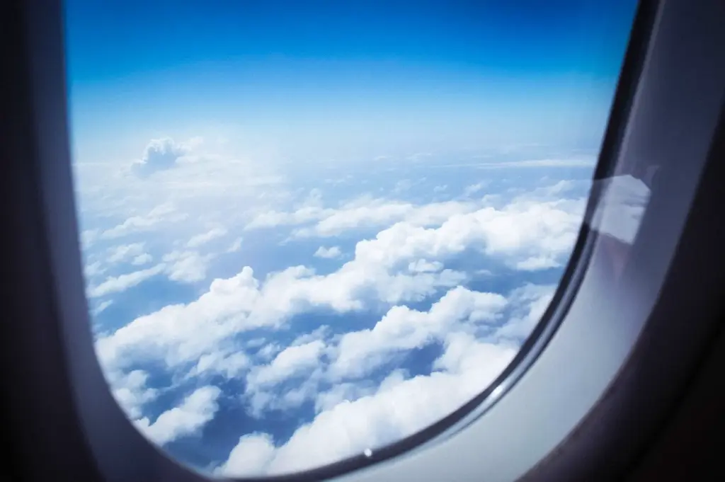View of white clouds and blue sky from an airplane window