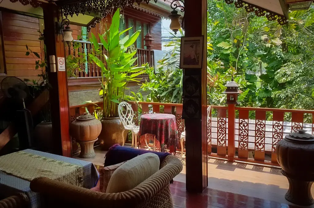 Cozy wooden veranda at Baifern Homestay in Ayutthaya, Thailand, featuring traditional Thai architecture, tropical greenery, and a peaceful outdoor seating area.