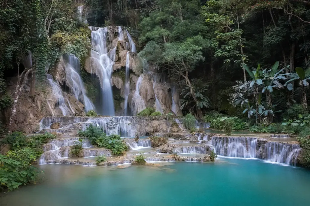 Kuang Si Falls near Luang Prabang, Laos, cascading over limestone terraces into a turquoise pool surrounded by lush tropical forest