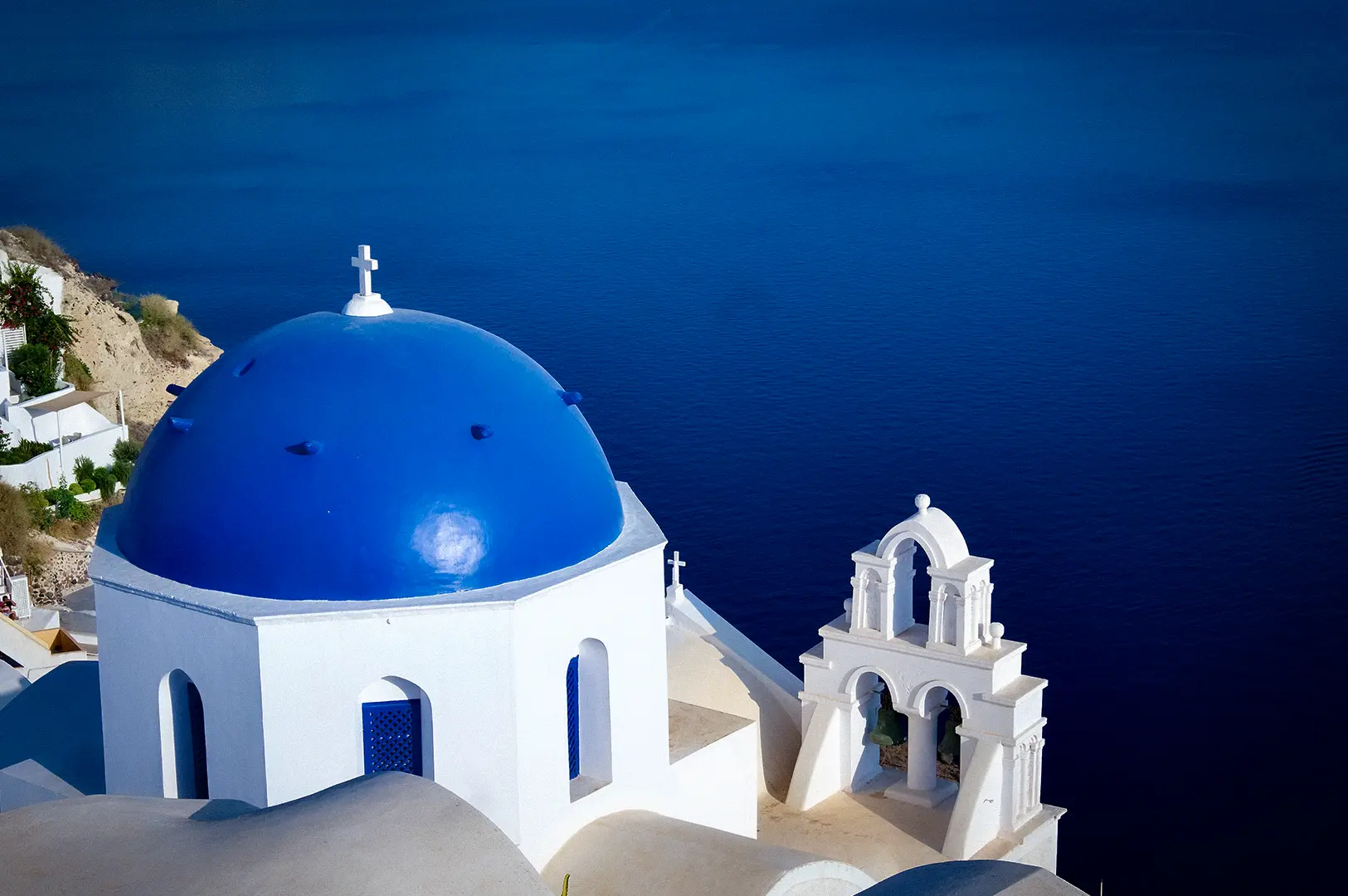 Santorini Greece blue domed church with whitewashed architecture overlooking the deep blue Aegean Sea