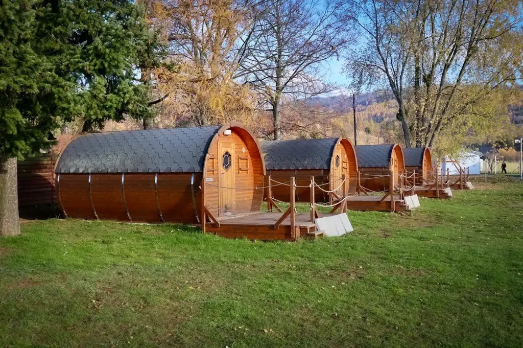 Wooden eco lodge cabins with curved roofs surrounded by trees and mountain scenery