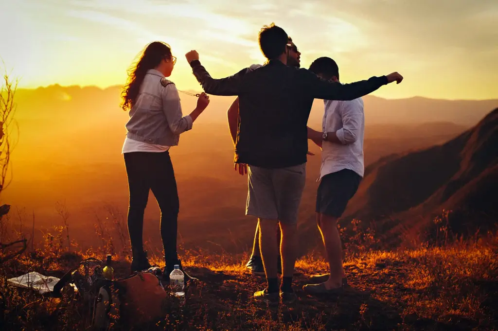 Group of friends enjoying a mountain sunset while traveling together.
