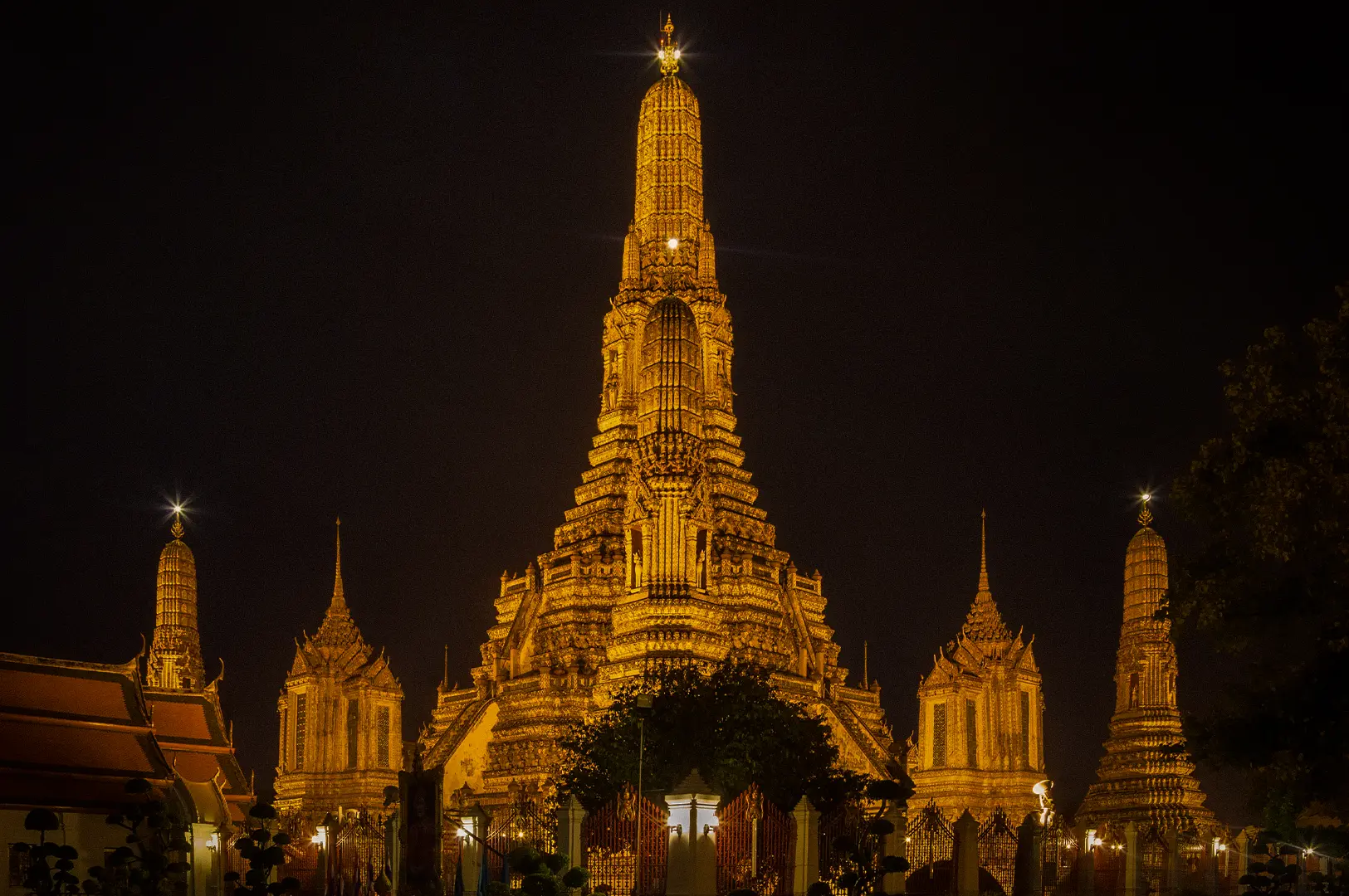 Wat Arun Bangkok illuminated at night with its ornate central temple spire and surrounding prangs