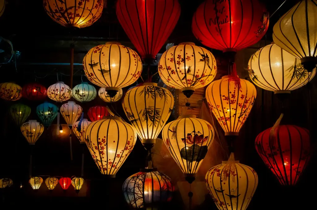 Colorful traditional Vietnamese lanterns glowing in Hoi An Ancient Town, featuring red, yellow, and cream lanterns with floral and bamboo designs.
