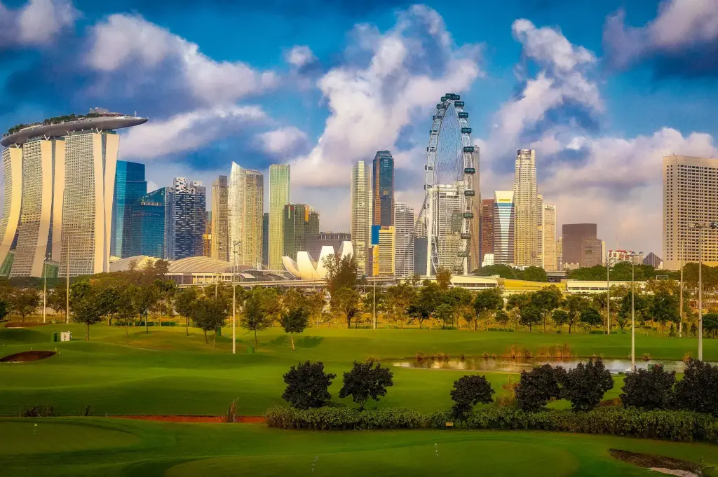 Singapore skyline featuring Marina Bay Sands, Singapore Flyer, ArtScience Museum, and surrounding city buildings viewed across a green golf course.
