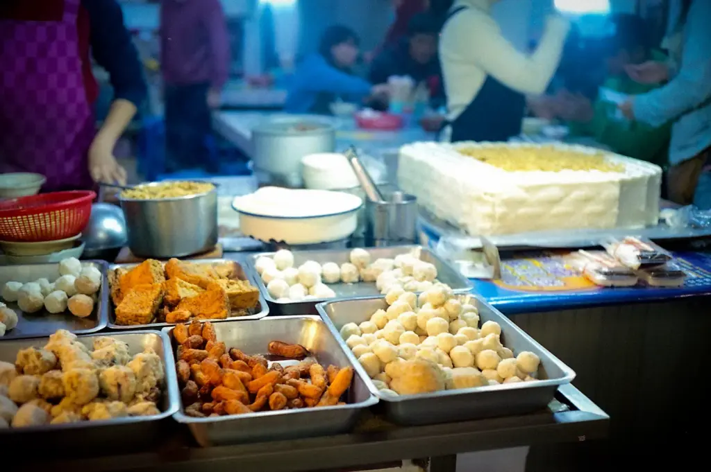Street food market stall with trays of fried snacks, dumplings, and other freshly prepared foods.