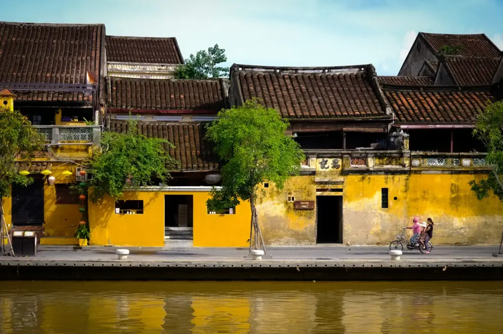 Row of historic yellow shophouses with tiled roofs along the riverbank in Hoi An Ancient Town