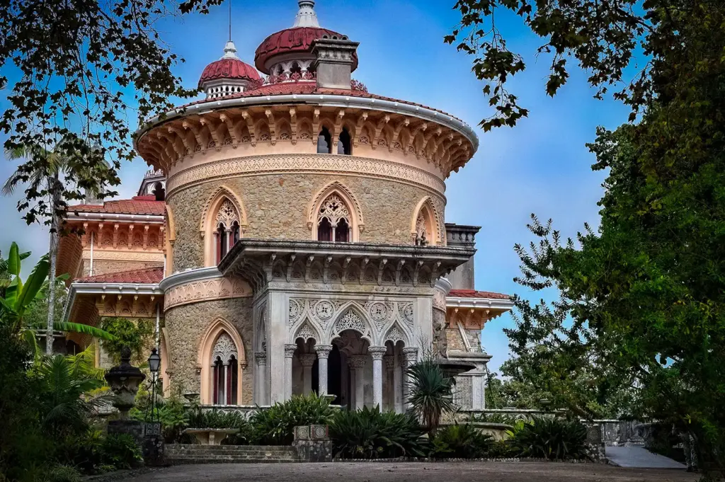 Exterior facade of the ornate Monserrate Palace in Sintra, Portugal, showcasing its unique blend of Gothic, Indian, and Moorish architectural styles surrounded by lush gardens